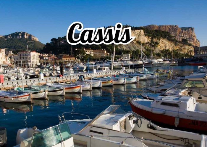 une vue en hauteur de cassis, on y voit le port et le cap canaille et en contre bas un taxi qui attend un client